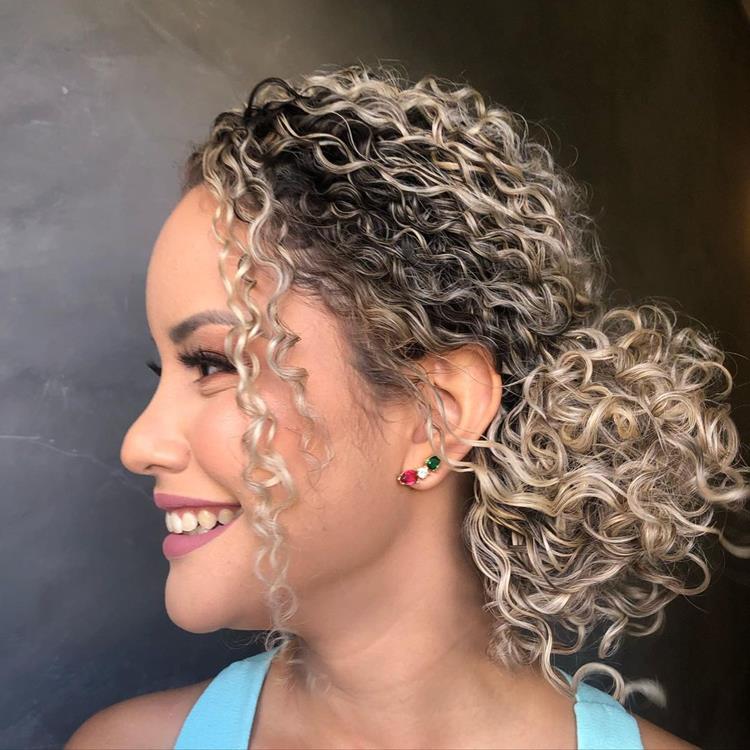mulher de lado com cabelo loiro, cacheado, preso em coque lateral baixo