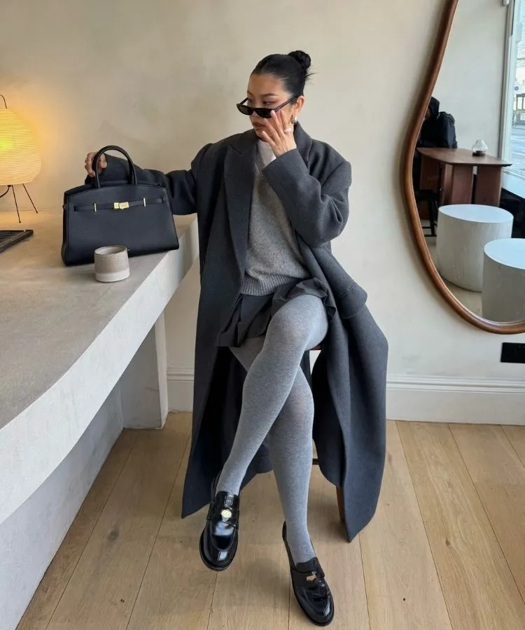 Mulher usando look com meia-calça cinza e mocassim preto