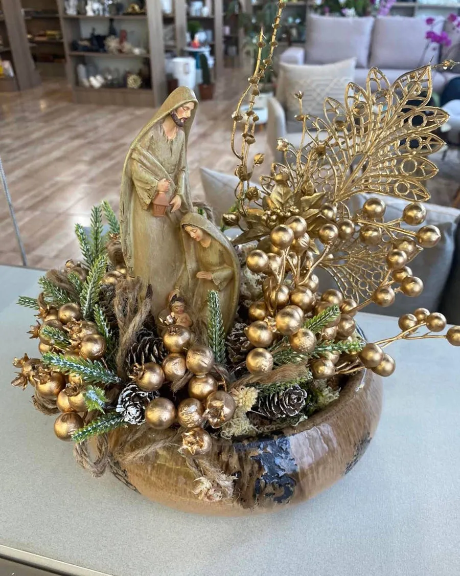 Arranjo de Natal dourado com imagem da Sagrada Família.