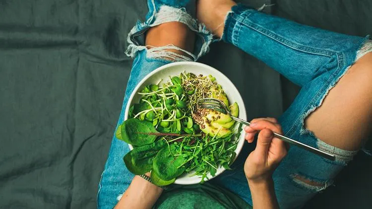 prato de comida vegana, folhas verdes escuras, abacate e brotos