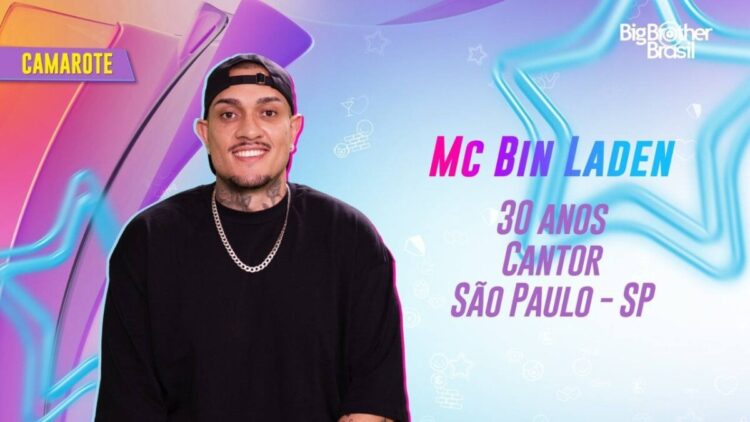 Mc Bin Laden em apresentação do BBB 24, usando boné preto para trás, blusa preta, corrente de prata e apresentação com nome, idade (30 anos), profissão (cantor) e cidade (São Paulo-SP)