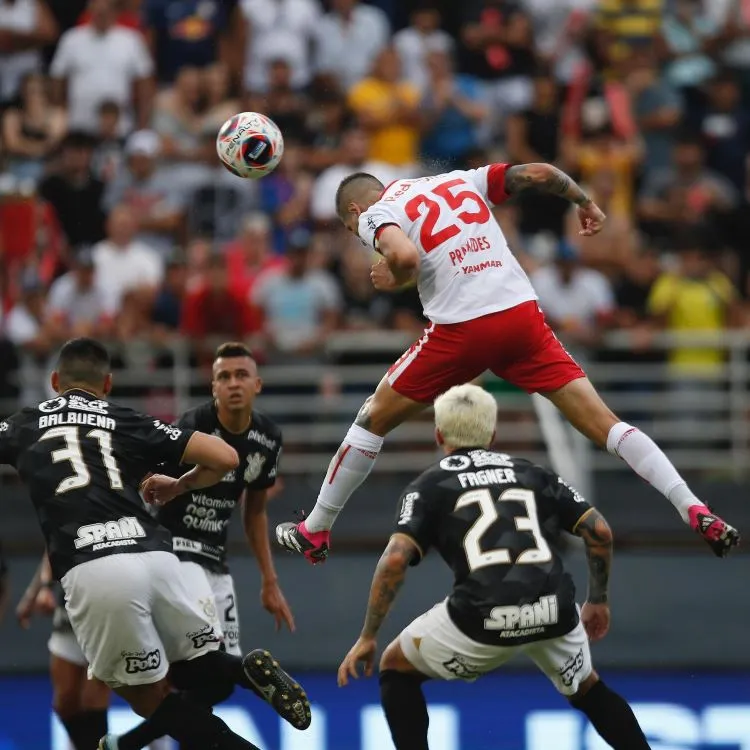 Praxedes, usando o primeiro uniforme do Bragantino, cabeceando a bola por cima do zagueiro Balbuena e do lateral Fagner.