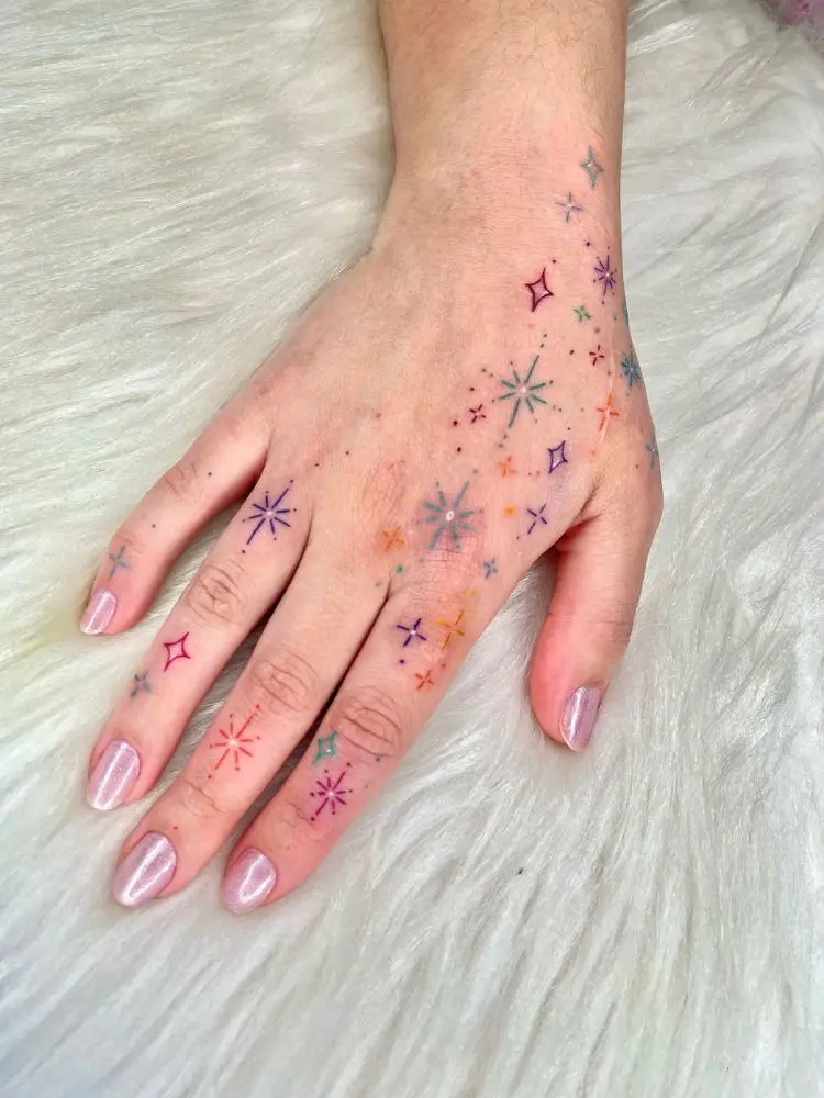 Mão tatuada com constelação colorida