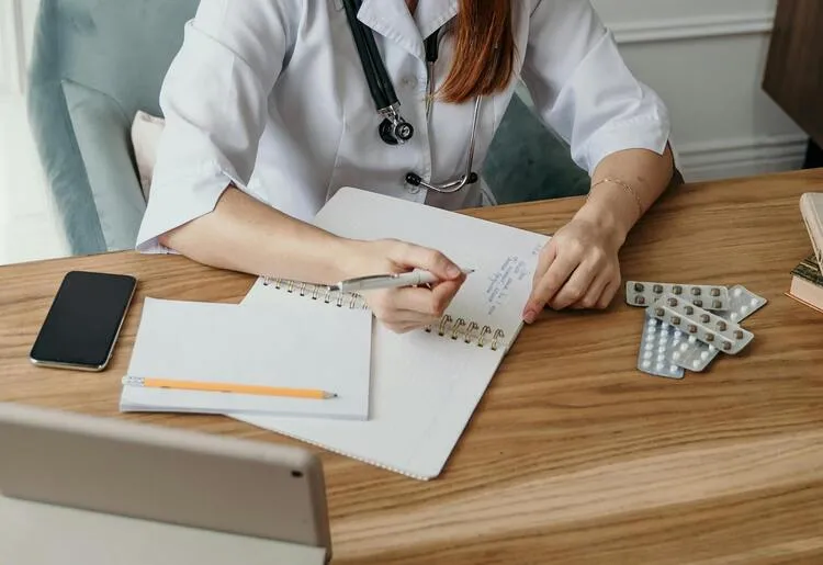 mãos femininas de uma médica escrevendo uma receita