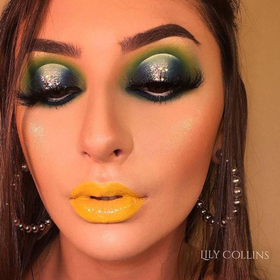 Foto de mulher com make verde e azul e batom amarelo