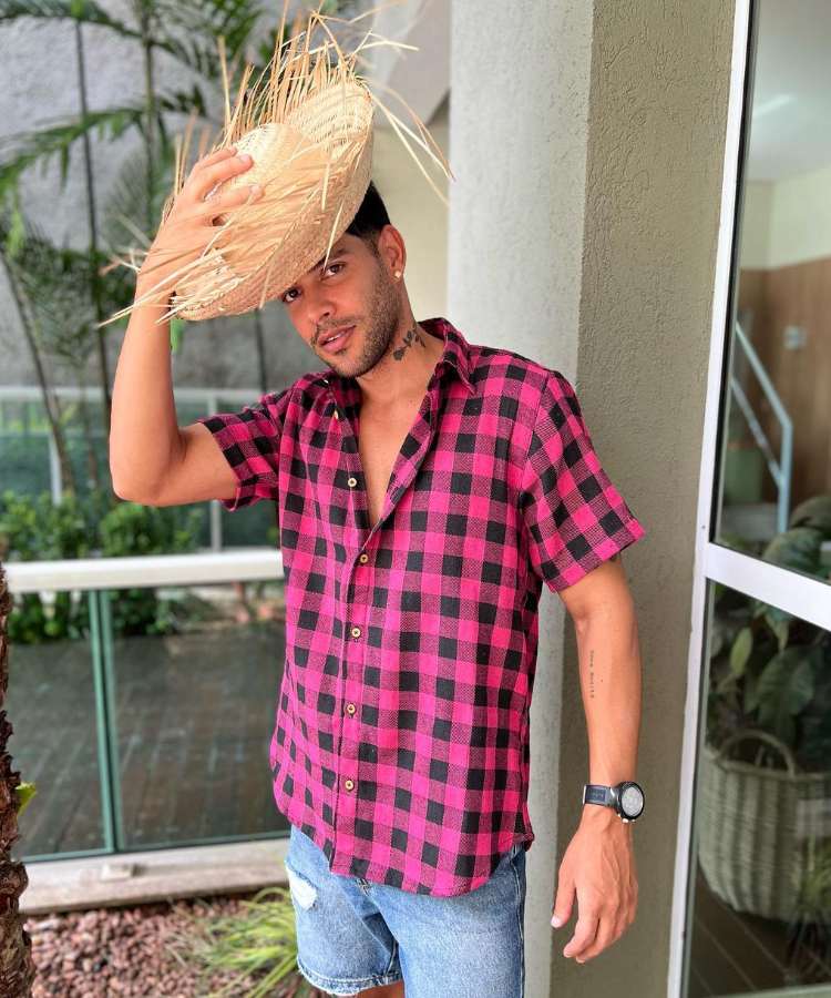 Homem com look de festa junina: camisa xadrez vermelha e chapéu de palha