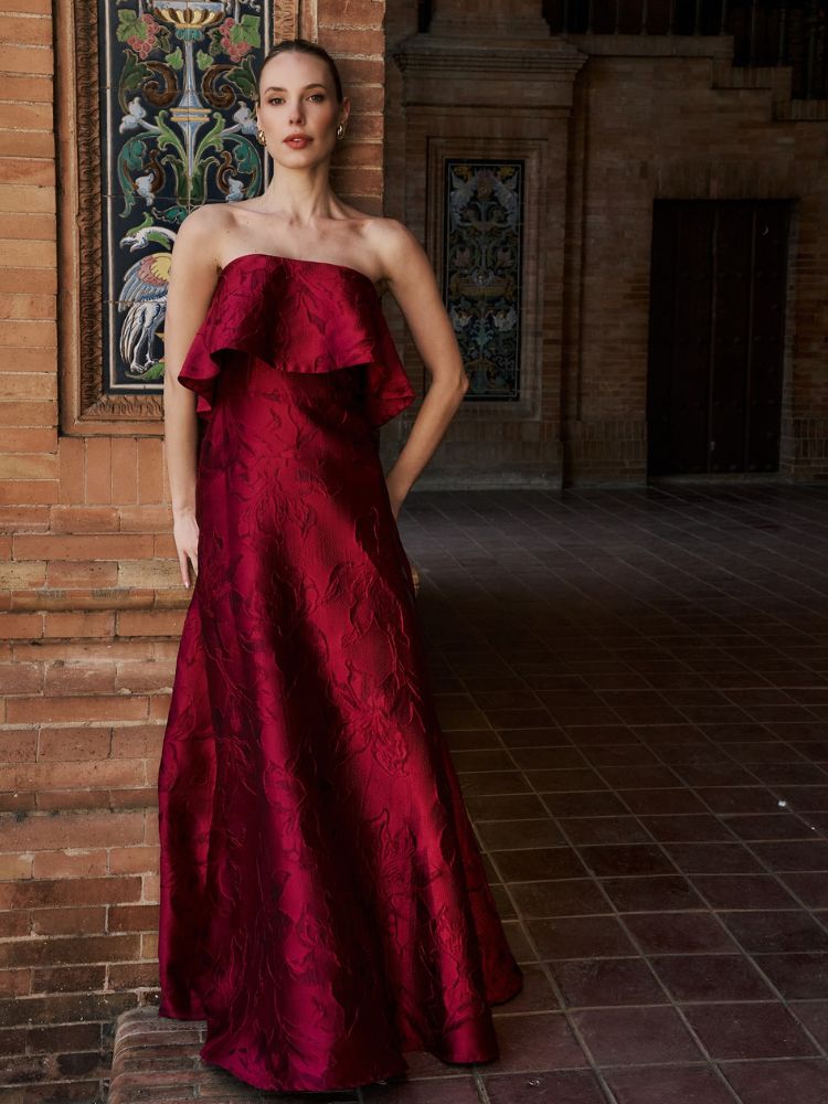 Mulher de pele clara usando vestido vermelho escuro texturizado com babado no colo e sem alça 