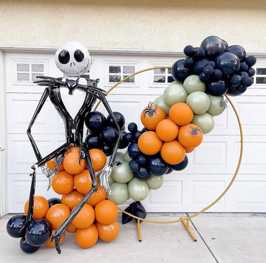 Decoração com bexigas pretas, douradas e laranjas, boneco do "Estranho Mundo de Jack", arco dourado e aranhas