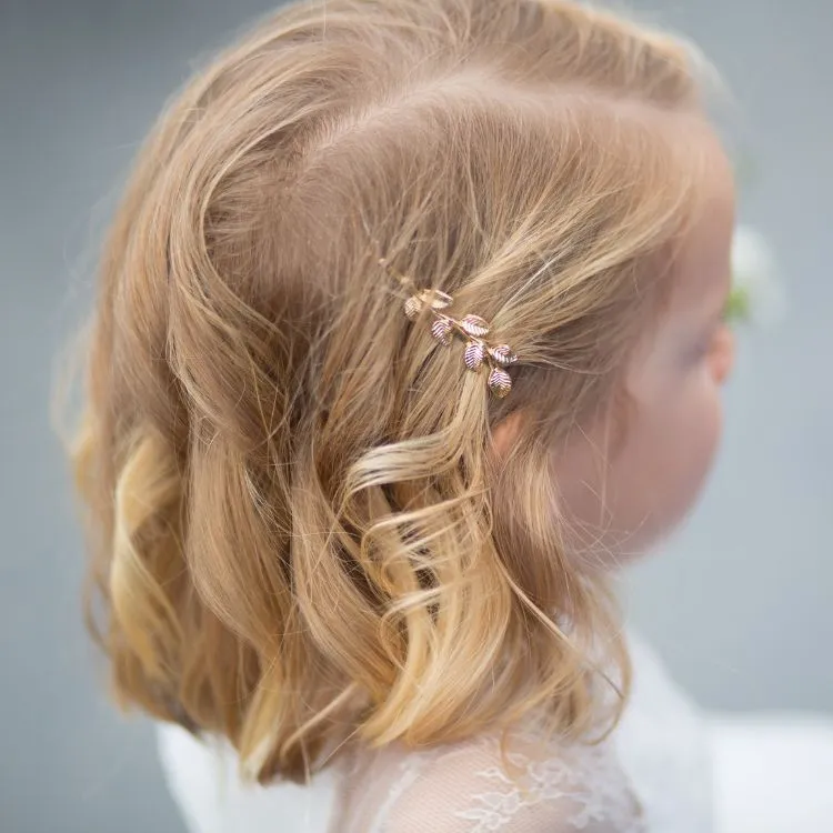 Menina de pele clara com cabelo chanel loiro e presilha de ramo