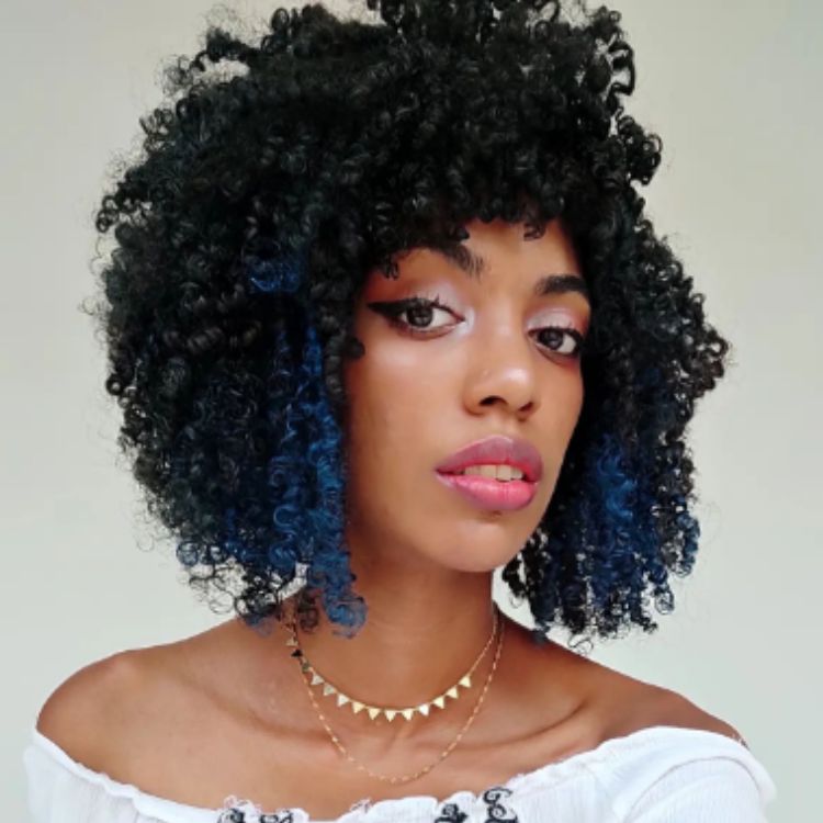 Mulher de pele negra usando  cabelo chanel crespo preto e azul
