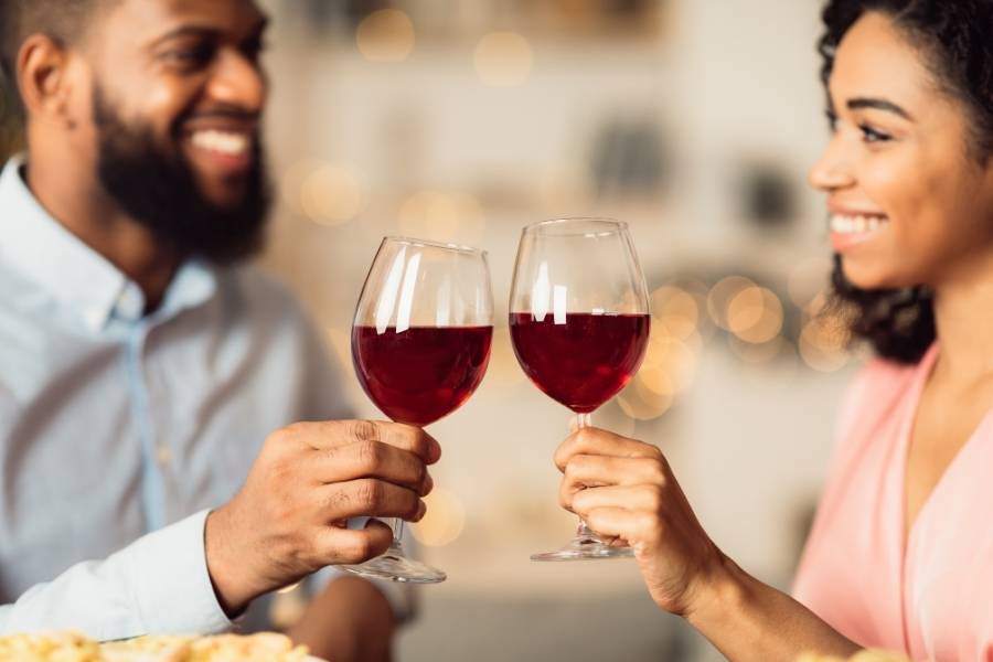 Casal garantindo os benefícios do vinho com uma taça cada.
