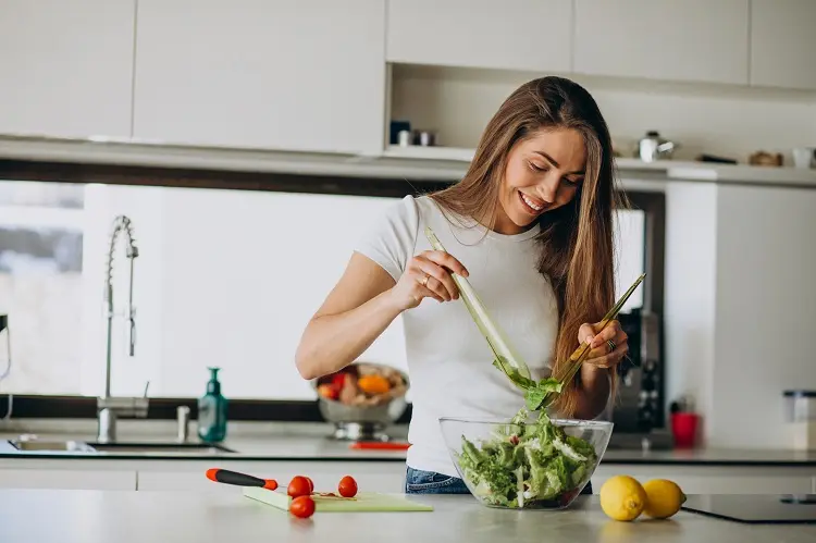 mulher sorridente temperando salada