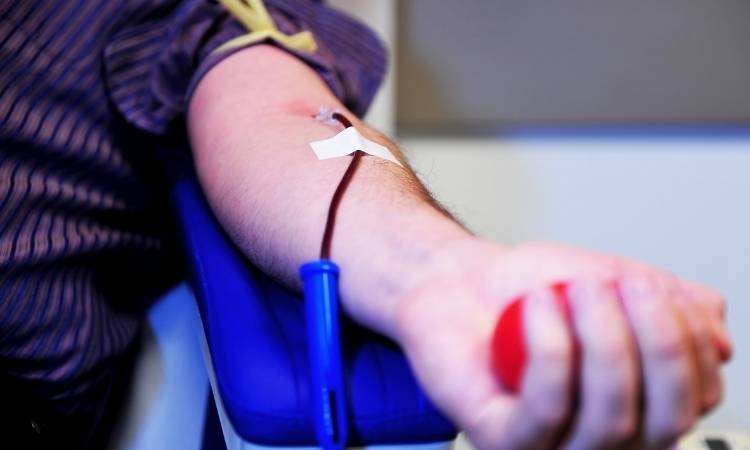 Homem doando sangue na campanha Junho Laranja.