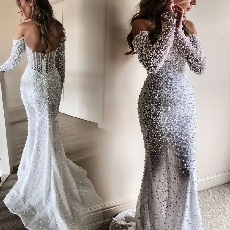 Mulher de pele clara usando vestido de noiva sereia com pérolas de costas para espelho