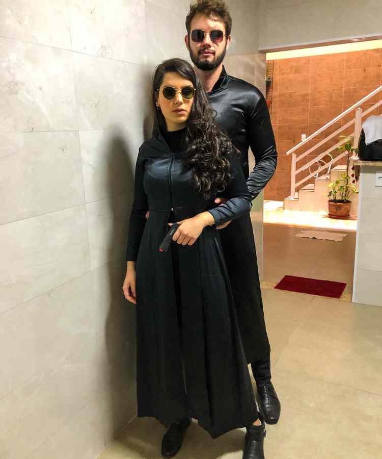 Traje de Dia das Bruxas para namorados: Matrix. Ambos usam roupa preta de couro e óculos de sol
