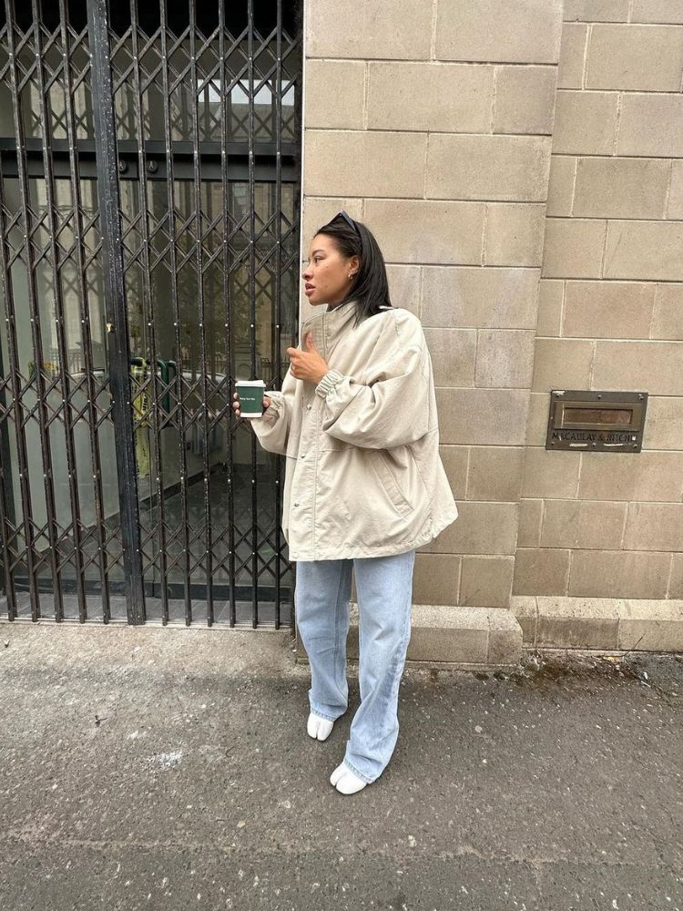 mulher usando casaco, calça jeans e sapatilha branca