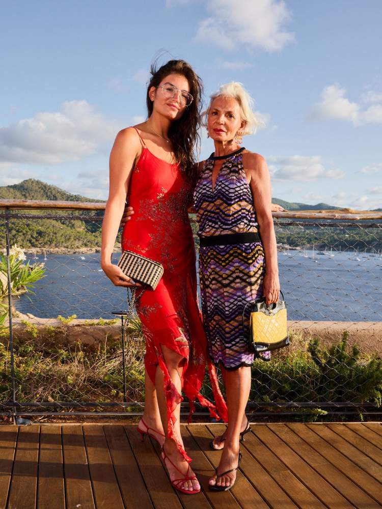 Cheyenne usando vestido vermelho e Grace usando vestido colorido com mar ao fundo