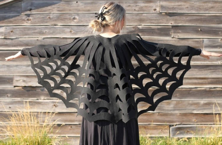 Pessoa de pele clara de costas usando vestido longo preto e capa de teia de aranha vazada preta