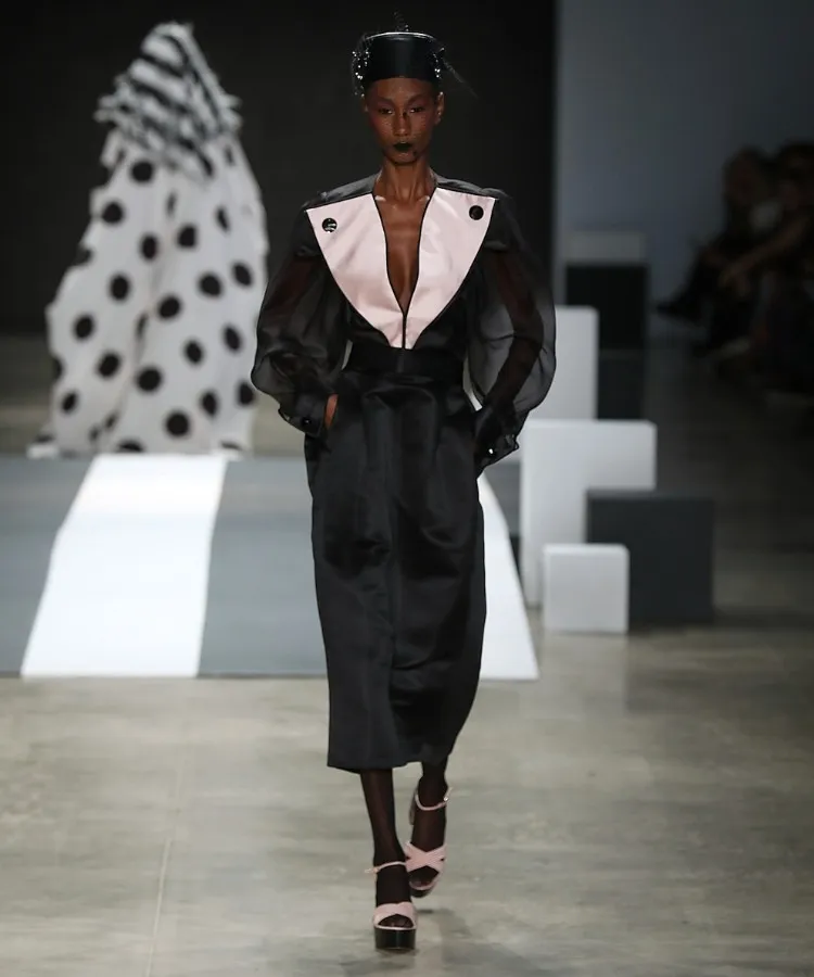 Foto de modelo usando look de alfaiataria em cetim preto no desfile de chapéus de Davi Ramos no SPFW N60