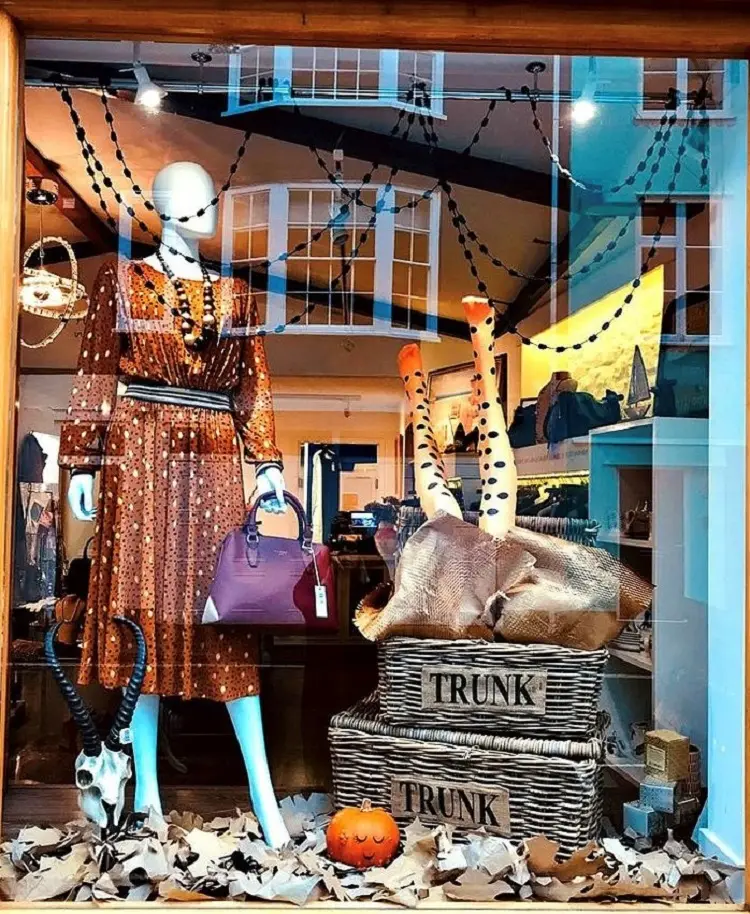 Loja com decoração de Halloween, com manequim de vestido laranja e teias 