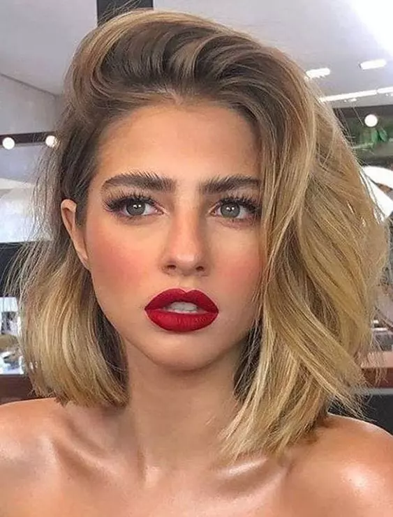 Mulher com cabelo loiro médio usando batom vermelho