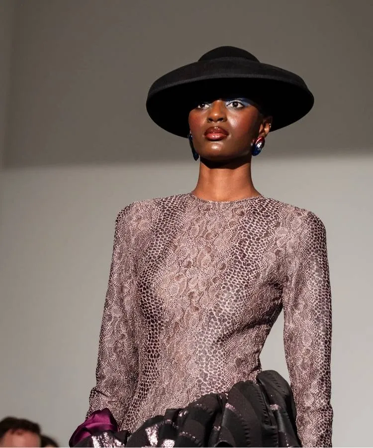 Modelo usando chapéu preto e top com estampa de cobra no desfile de Thayná Caiçara na Semana de Alta-Costura de Paris 2026