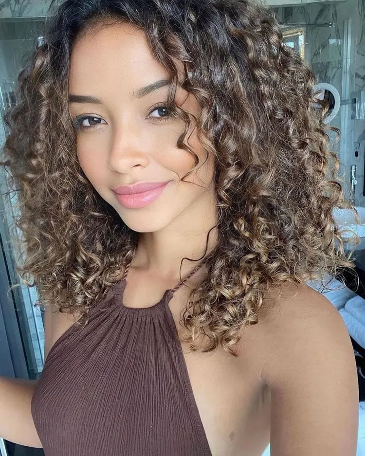 mulher de cabelo médio cacheado castanho e franja média