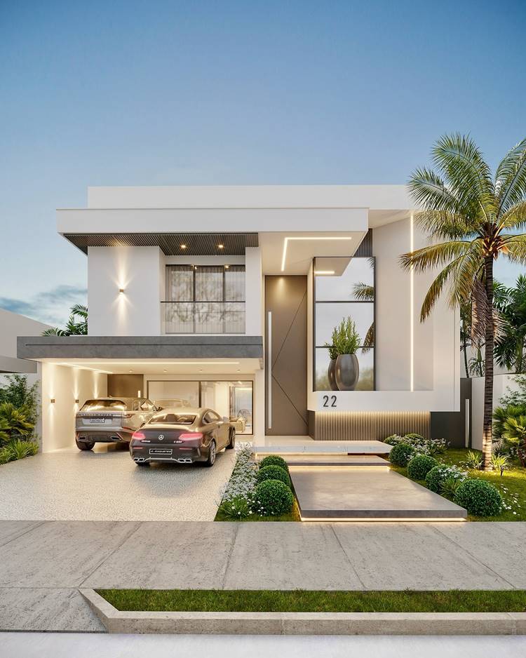 Fachada de casa moderna de dois andares com um telhado plano e linhas limpas. A casa é pintada de branco com algumas seções em cinza escuro para contraste. Há uma garagem na lateral esquerda da imagem com dois carros; um prata e um escuro. O número da casa “22” está visível ao lado da porta da frente que é grande e cinza. Um jardim bem cuidado com arbustos, gramas e uma palmeira alta está visível na frente da casa.