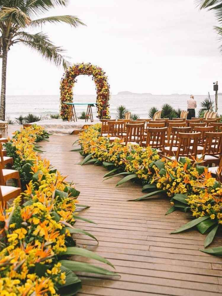 Decoração de casamento na praia com flores amarelas.