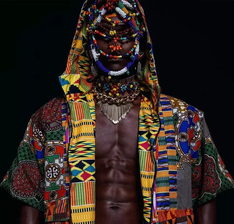 Modelo masculino com blusa com capuz colorida, e adereços coloridos no rosto.
