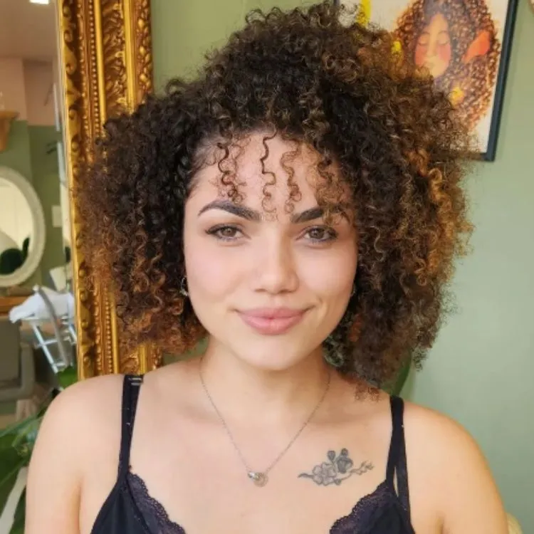 Mulher de pele clara com cabelo chanel cacheado e franja