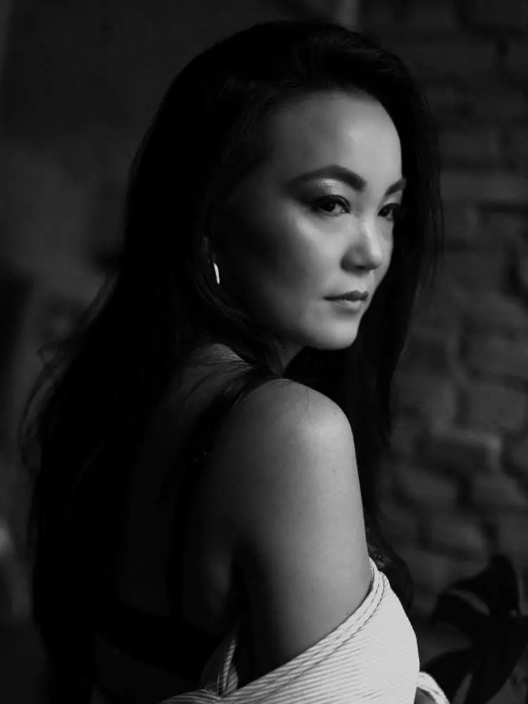 Mulher não-modelo com mais de 30 anos em ensaio fotográfico, usando sutiã preto e outra peça de listras