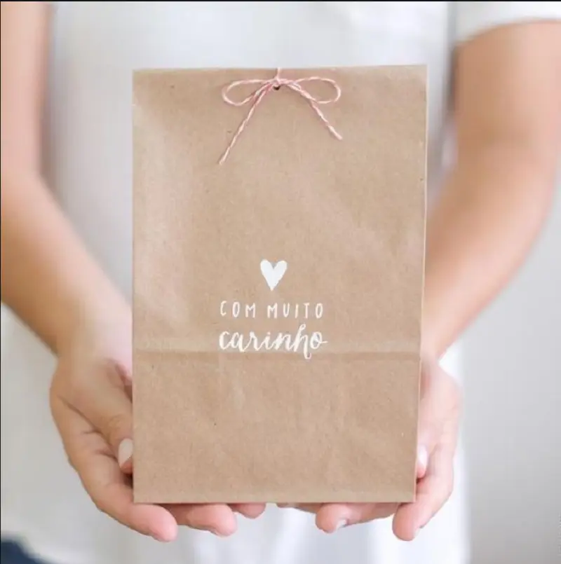 mãos segurando sacola de papelão com os dizeres "com muito carinho"