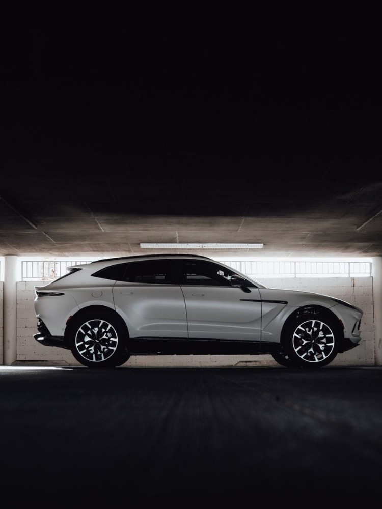 Aston Martin DBX branca de lado em ambiente fechado e escuro