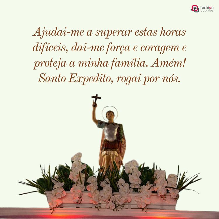 Imagem de uma estátua de Santo Expedito, com auréola, segurando uma cruz no alto. A base está decorada com flores brancas e verdes. Texto acima diz: "Ajudai-me a superar estas horas difíceis... Santo Expedito, rogai por nós."