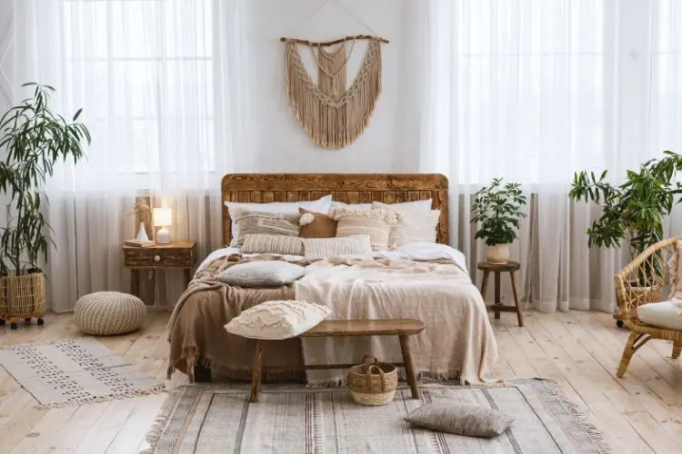 Quarto estilo boho com macramê na parede, cama baixa, pufe de tricô, tapete colorido e planta