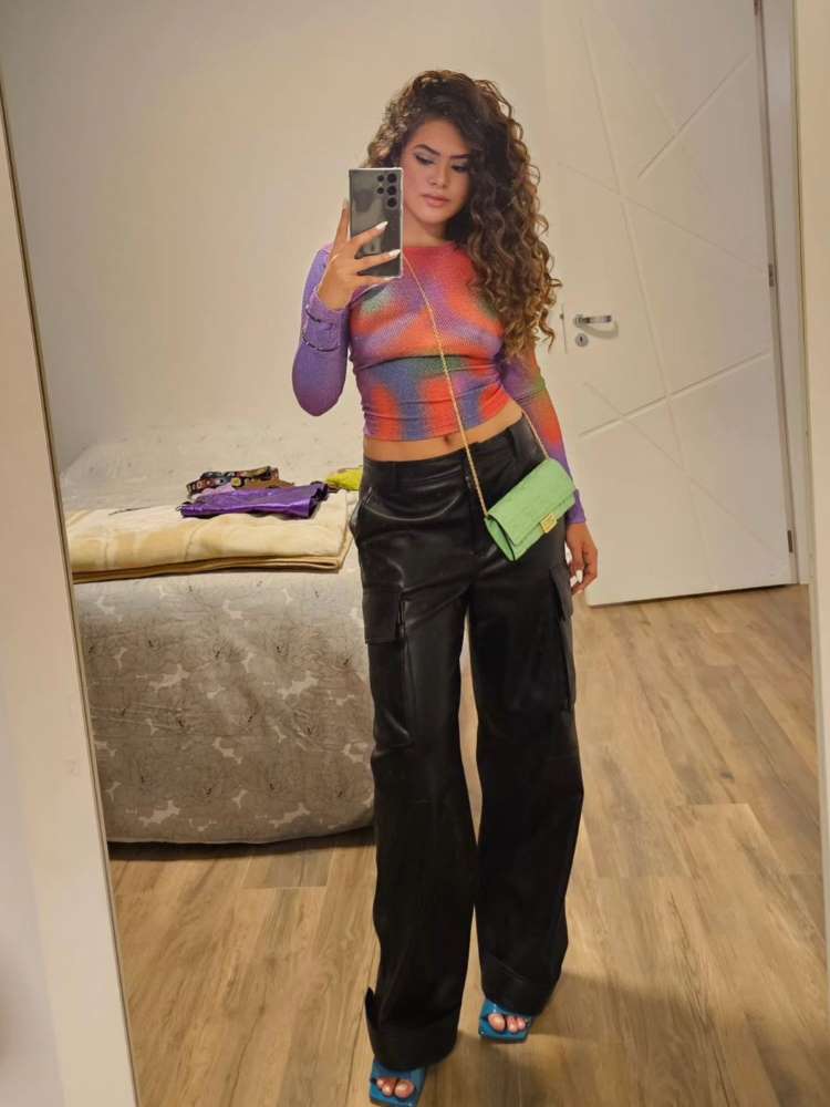 Maisa usando cropped de manga comprida meio transparente colorido, calça preta e pequena bolsa verde