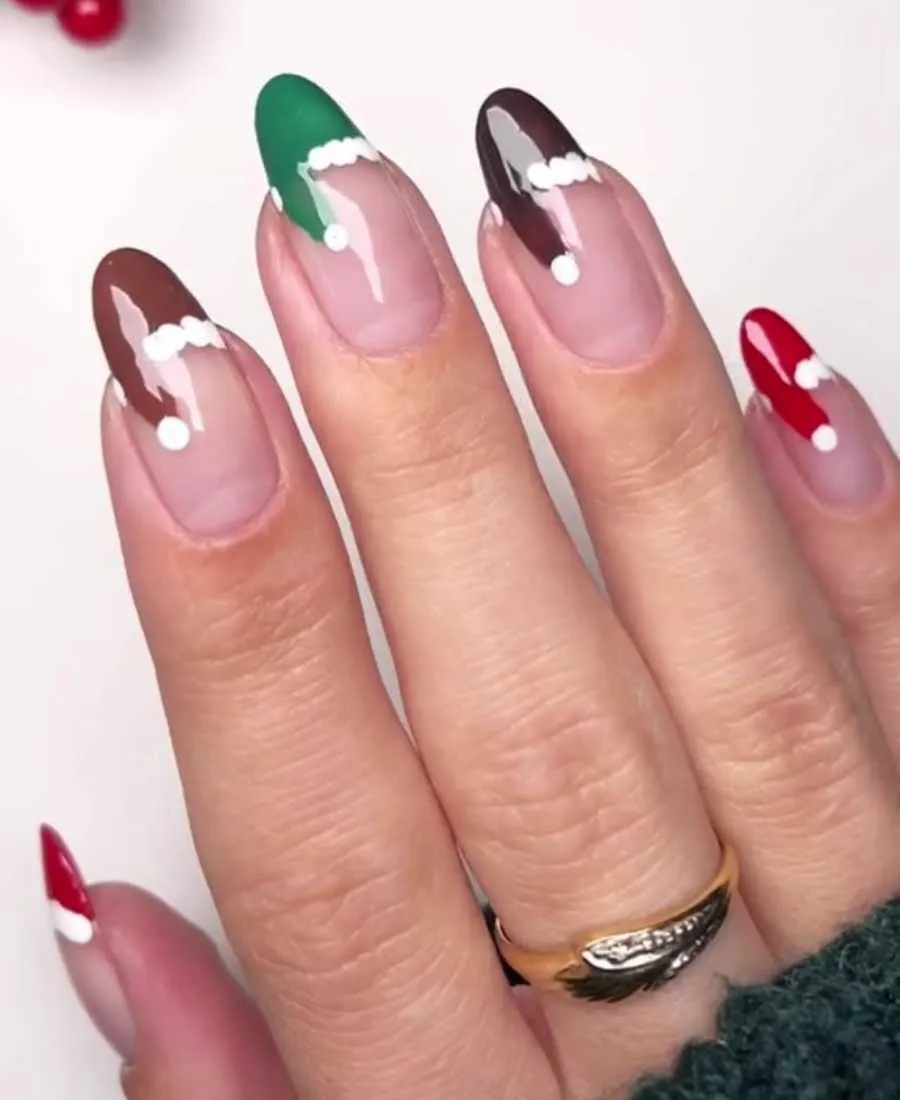 Foto de mão de pele clara com unhas almond pintadas com francesinha de gorro do Papai Noel