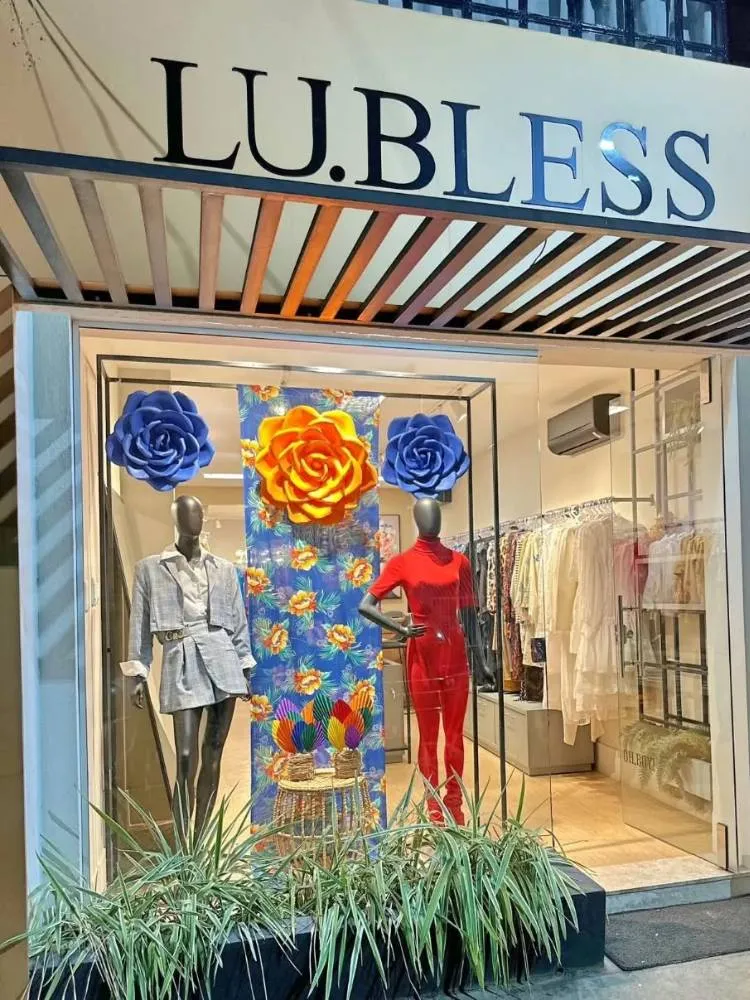 Vitrine de loja de roupas femininas com chita pendurada e maxi flores laranjas e azuis 