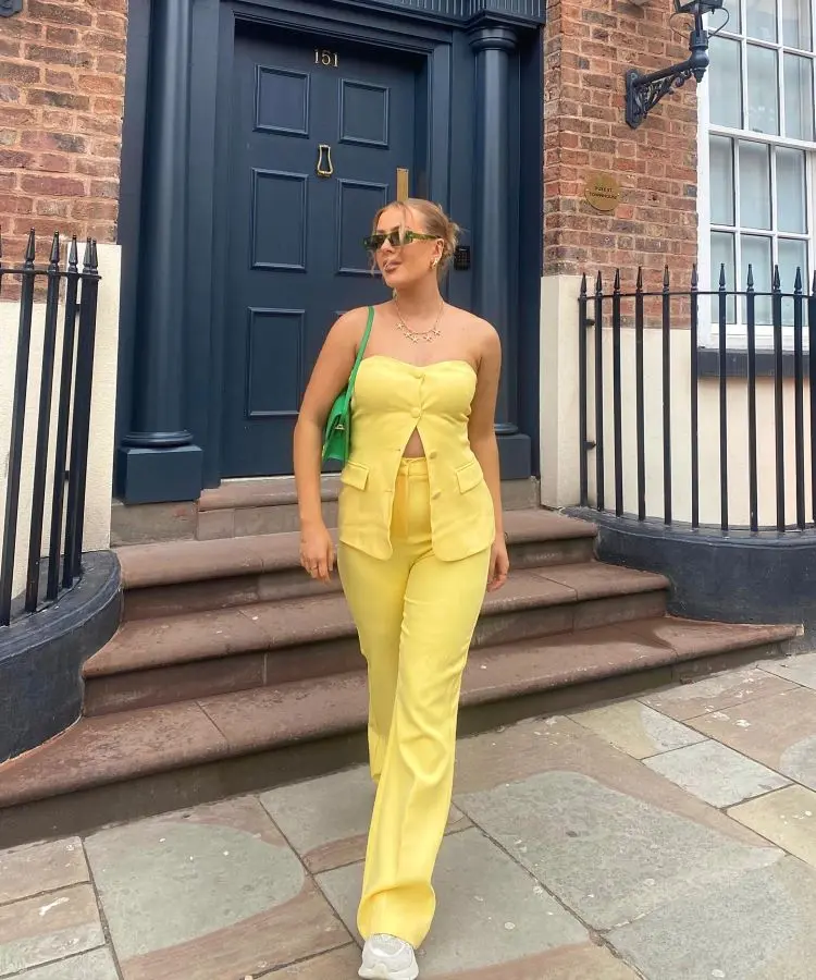 Mulher com conjunto amarelo, tênis branco e bolsa verde para torcer pelo Brasil