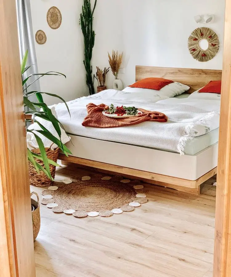 Quarto de casal simples, decorado com objetos de palha na parede, chão e como vasos de plantas