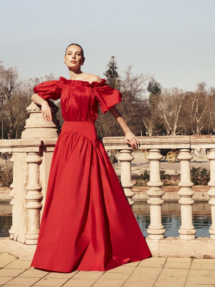 Mulher de pele clara usando vestido vermelho de mangas bufantes e babados