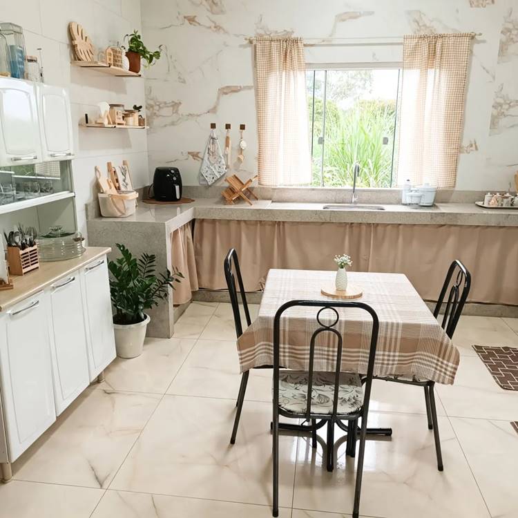 Pia e bancada com cortina em cozinha simples com mesa, prateleiras e armário