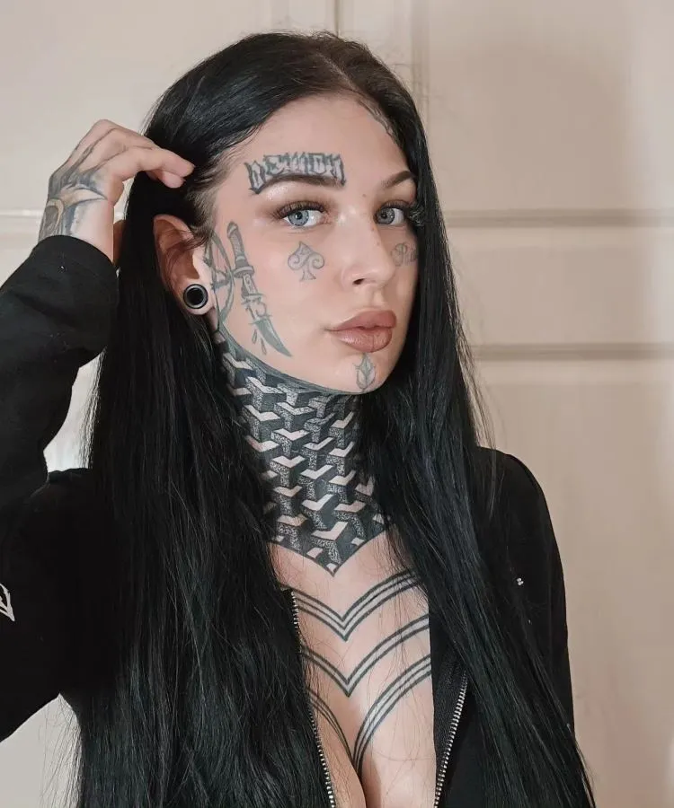 A imagem mostra uma pessoa de costas com cabelo castanho e alargadores pretos nas orelhas. Ela tem uma tatuagem no pescoço de um design abstrato em preto, com linhas e formas geométricas que se estendem da base do crânio até os ombros. A tatuagem é complexa e artística.




