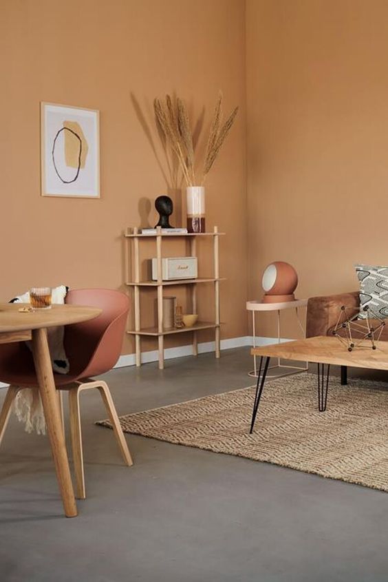 Sala de estar e jantar com parede bege e móveis e decorações em tons terrosos 