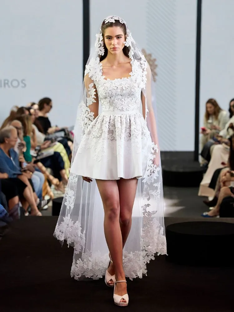 Mulher de pele clara com vestido de noiva curto com renda e véu também rendado