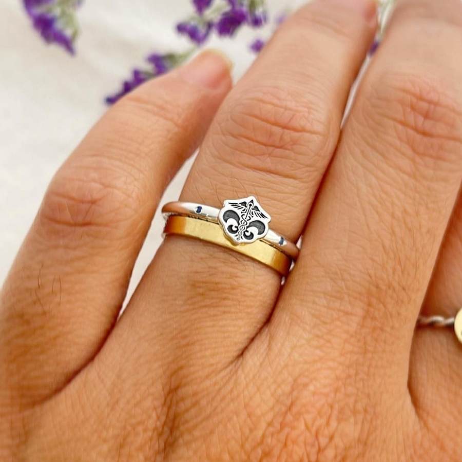 Mulher de pele clara com anel dourado e prateado de pedra azul no dedo anelar