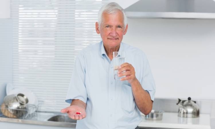 Idoso tomando remédio para Mal de Parkinson.