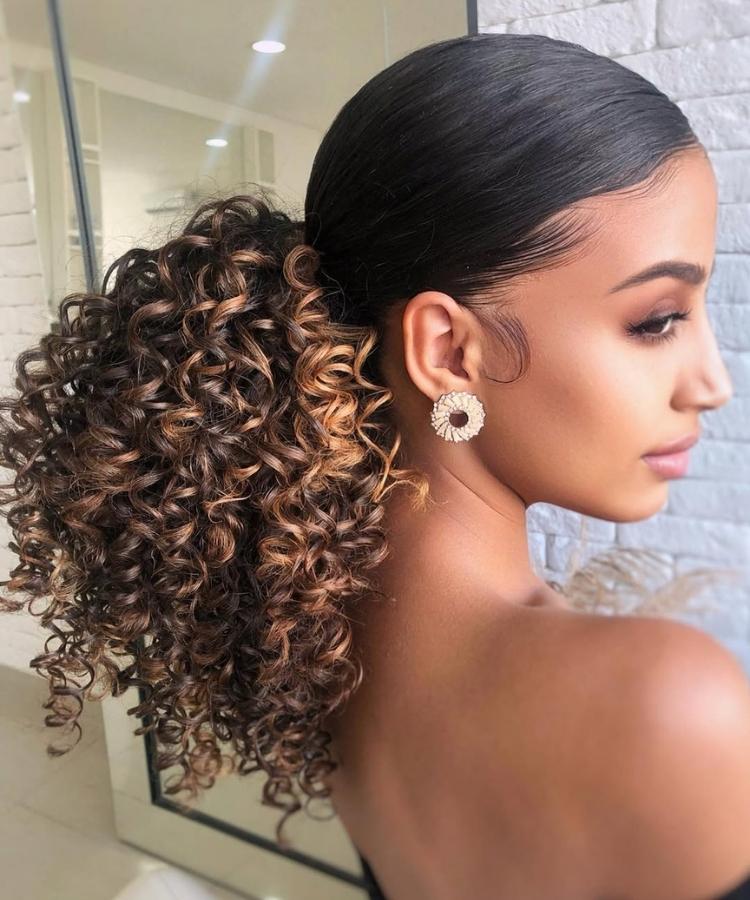 Foto de mulher negra usando rabo de cavalo baixo em seu cabelo cacheado longo