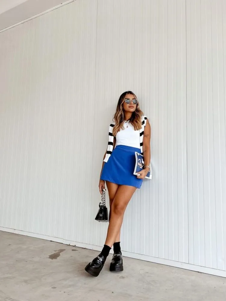 Mulher usando mocassim com saia azul